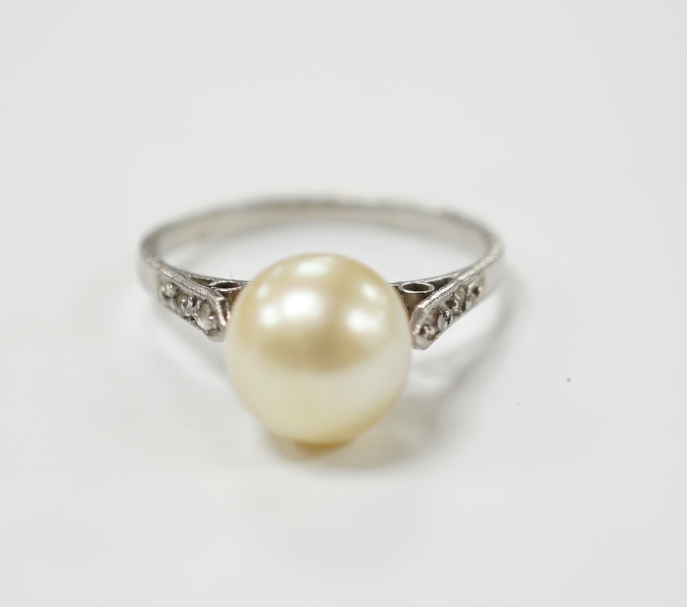 A white metal solitaire cultured pearl ring with diamond set shoulders, size J